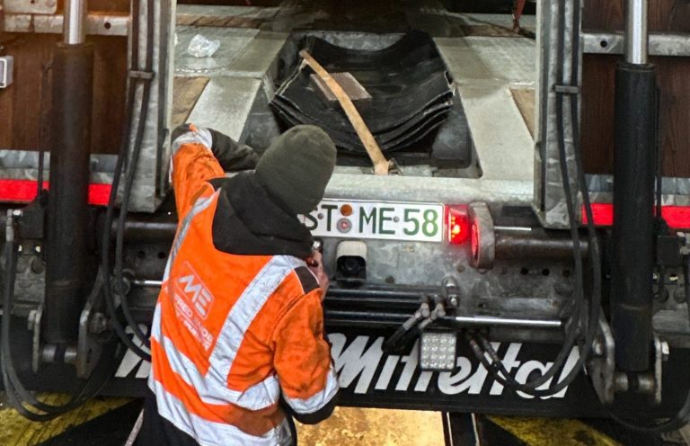 Ein Mitarbeiter der Manfred Ende GmbH arbeitet in Warnschutzkleidung am Heck eines modernen Nutzfahrzeugs. Die Aufnahme zeigt den praktischen Arbeitsalltag im Bereich Transport und Baustellenlogistik. So sieht Karriere bei der Manfred Ende GmbH aus