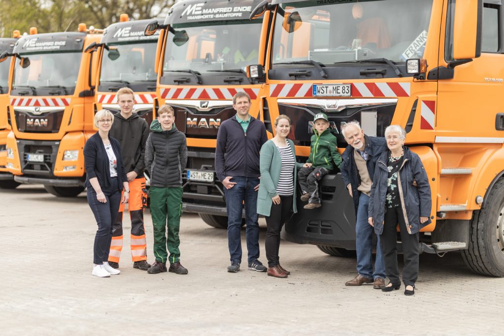 Gründerfamilie von Manfred Ende – Baustoffhandel & Transporte vor dem firmeneigenen LKW-Fuhrpark.